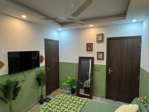 a living room with a flat screen tv and two doors at Tropical vibes Private, Terrace, Cozy space- Gurgaon and NCR in Gurgaon