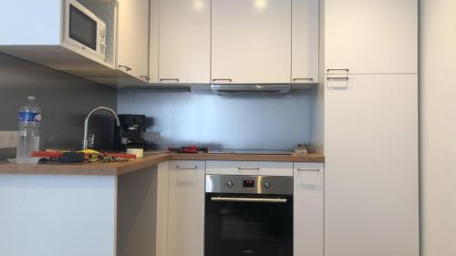 une cuisine avec des armoires blanches et un four noir dans l'établissement studio, à Claviers