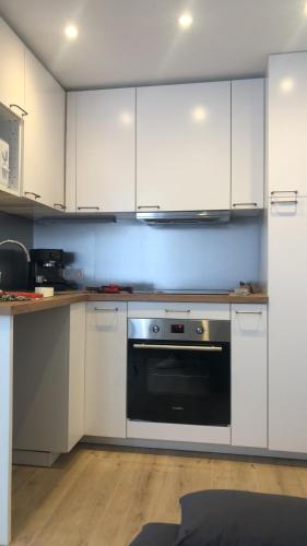 une cuisine avec des armoires blanches et un four noir dans l'établissement studio, à Claviers