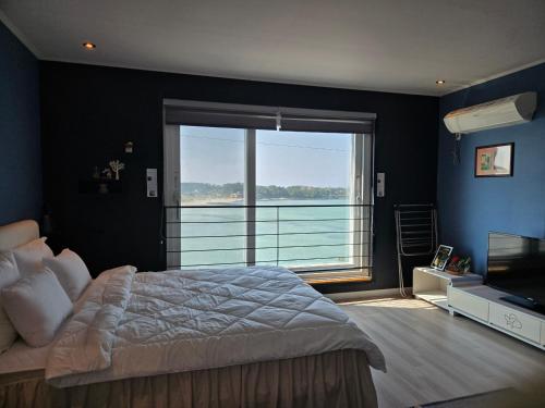 a bedroom with a large bed and a large window at Jeju Gaviota Pension in Jeju