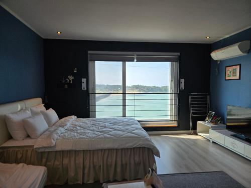 a bedroom with a large bed and a large window at Jeju Gaviota Pension in Jeju