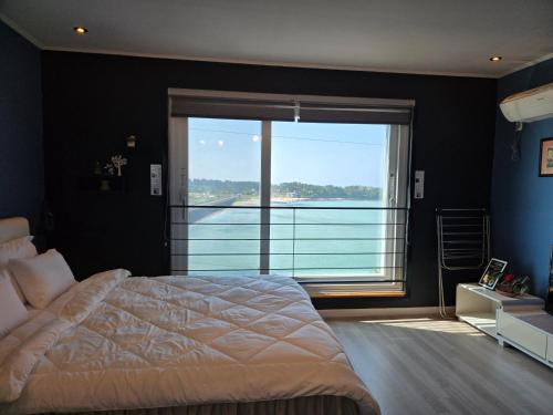a bedroom with a large bed and a large window at Jeju Gaviota Pension in Jeju