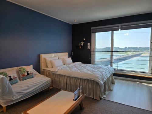a bedroom with a bed and a couch and a window at Jeju Gaviota Pension in Jeju