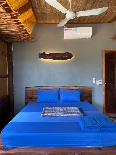a blue bed in a room with a ceiling fan at Lazy Beach in Koh Rong Sanloem
