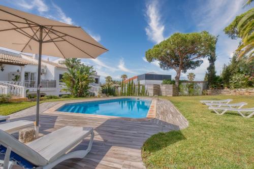 a swimming pool with chairs and an umbrella at Casa Teles in Quarteira
