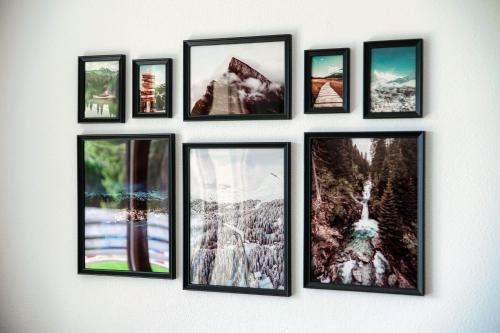 a group of framed pictures on a wall at Sanbe Garden by Quokka 360 - flat with garden in San Bernardino in Mesocco