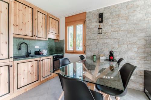 a kitchen with a glass table and black chairs at Sanbe Garden by Quokka 360 - flat with garden in San Bernardino in Mesocco