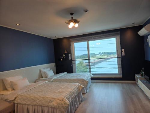 two beds in a room with a large window at Jeju Gaviota Pension in Jeju