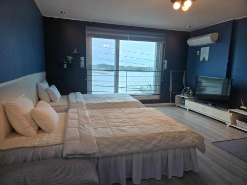 a large bedroom with a large bed and a television at Jeju Gaviota Pension in Jeju