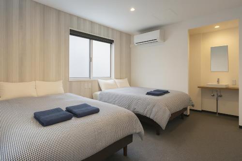 two beds in a hotel room with towels on them at Port House Honmachi in Tokyo