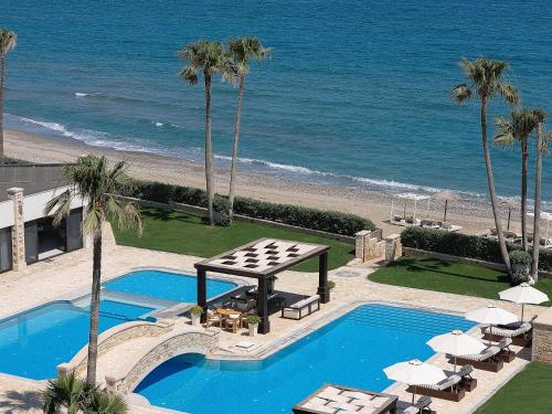 a pool with a table and chairs next to the beach at Paralia Beachfront Residence in Georgioupolis