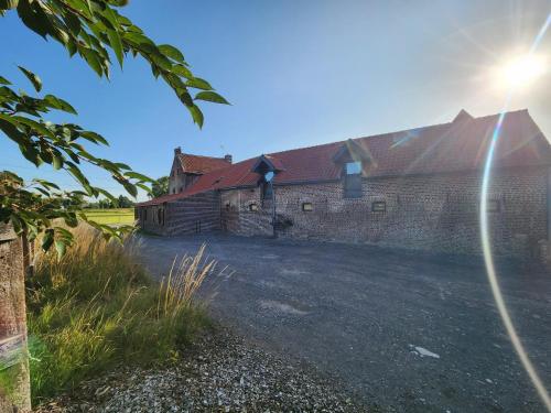 a brick building with the sun shining behind it at Ferme de la Forterie in Verlinghem
