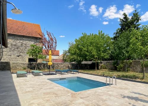 - une piscine dans une cour avec un bâtiment en briques dans l'établissement Le Clos de Joux - Charmante Maison en Bourgogne, à Joux-la-Ville