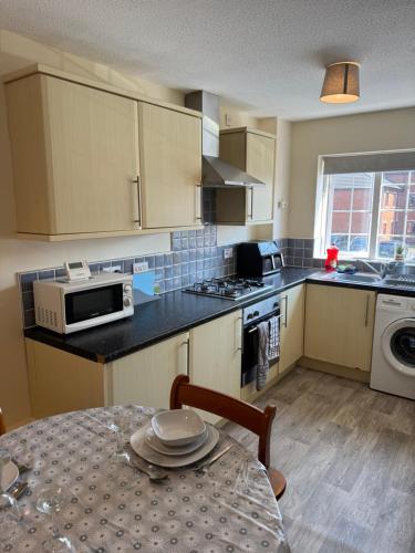 a small kitchen with a table and a microwave at Spacious, Sleeps 14, 3 bathrooms, Central, Parking, Grimsby in Grimsby