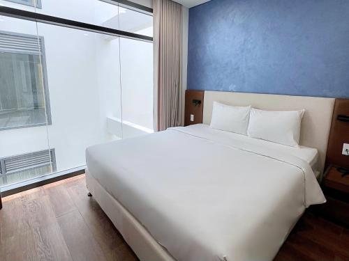 a white bed in a room with a large window at Glamour Boutique Hotel in Phan Rang