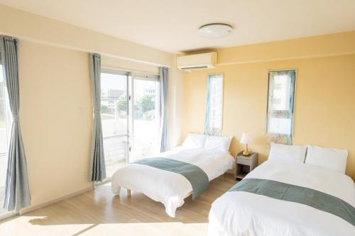 Dos camas en una habitación con ventana. en ハレルヤ石垣, en Ishigaki Island