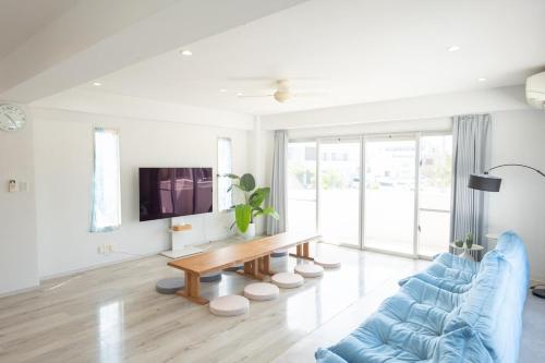 Una sala de estar con una mesa y un sofá azul. en ハレルヤ石垣, en Ishigaki Island
