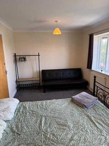a bedroom with a bed and a black couch at Spacious, Sleeps 14, 3 bathrooms, Central, Parking, Grimsby in Grimsby