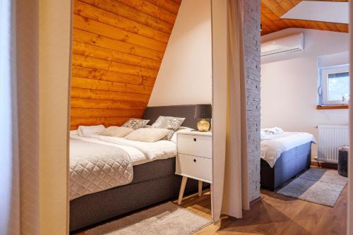 a bedroom with two beds and a wooden wall at Kuća za odmor Šumska vila in Duga Resa