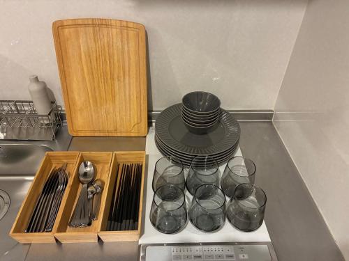 a kitchen counter with plates and cups on a stove at trive meieki nishi 106 最大6名宿泊可 名古屋駅まで1駅 太閤通駅徒歩4分 角部屋 無料駐車場付き in Nagoya