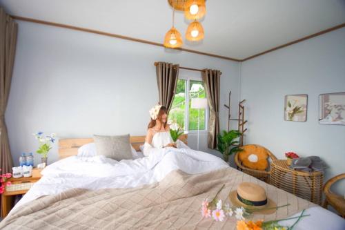 a woman sitting on a bed in a bedroom at ชิวชิวแคมป์ ภูชี้ฟ้า in Ban Huai Han