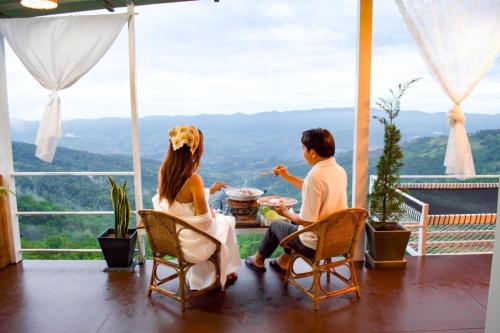 a man and a woman sitting at a table on a balcony at ชิวชิวแคมป์ ภูชี้ฟ้า in Ban Huai Han