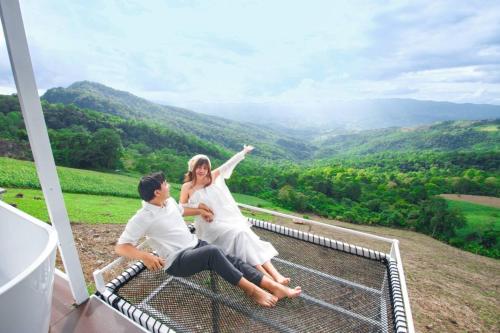 a man and a woman sitting on a bench on a porch at ชิวชิวแคมป์ ภูชี้ฟ้า in Ban Huai Han