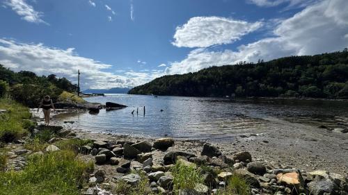a woman walking on the shore of a river at Cabin by the lake with 3 bedrooms in Kvam