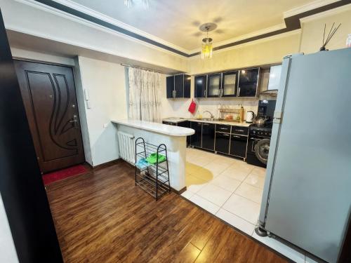 a kitchen with black cabinets and a white refrigerator at Downtown High view Balcony! in Toshkent-Passajir Bekati