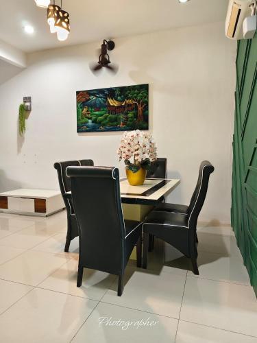 a dining room table with chairs and a vase of flowers at Laman Baraqah in Kuantan