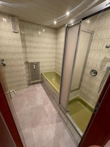 a bathroom with a shower and a green tub at Modernes Apartment mit Balkon und Aussicht in Ansbach
