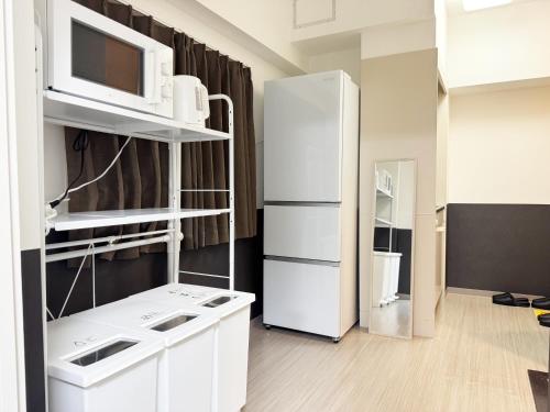 a kitchen with a white refrigerator and a microwave at Hostel Inn Yokohama Isezakicho in Yokohama