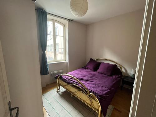 a bedroom with a bed with purple sheets and a window at sainte anne petite venise colmar in Colmar