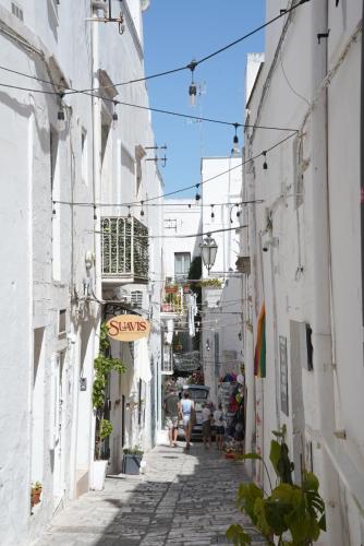 a narrow alley with white buildings and people sitting at Casa Giglio in Ostuni