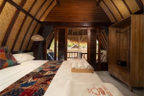 a bedroom with a bed with towels on it at Tricky Trees Sunset Bungalows in Gili Air