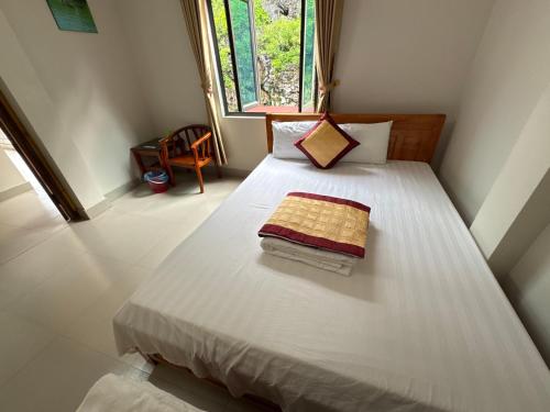 a bedroom with a bed with white sheets and a window at Ba Be Lake - Nhà Nghỉ Thư Nhạc in Bak Kan