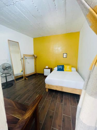 a bedroom with a bed and a yellow wall at Rincón pochutleco in San Pedro Pochutla