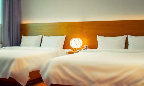 a hotel room with two beds and a lamp at Am Ort Hotel in Yeosu