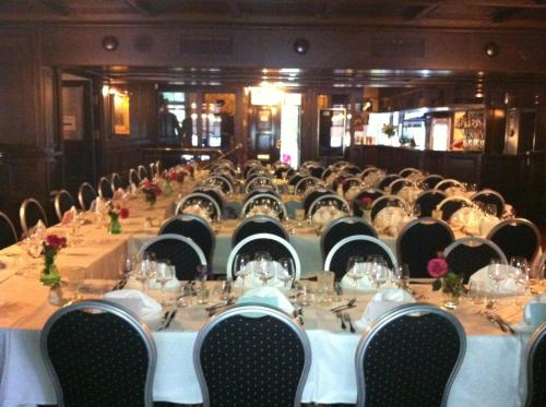 a long table with white tables and black chairs at Hotell Plevnagården in Malmköping