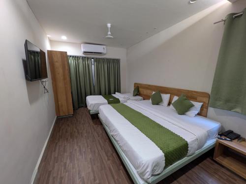 a bedroom with two beds and a television in it at Hotel Petal Inn in Nagpur