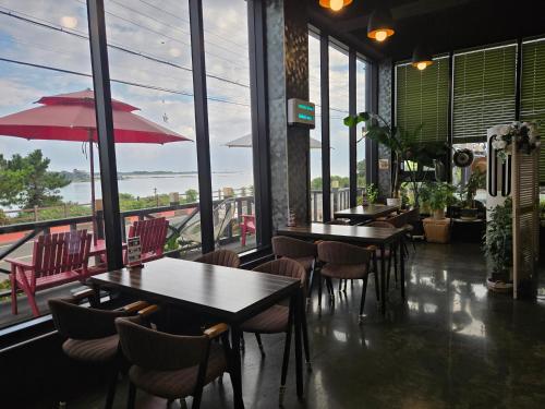 a restaurant with tables and chairs and large windows at Jeju Gaviota Pension in Jeju