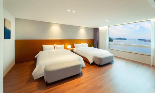 a bedroom with two beds and a large window at Am Ort Hotel in Yeosu