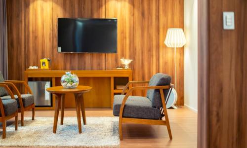 a living room with a tv and a table and chairs at Am Ort Hotel in Yeosu