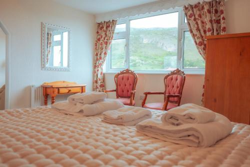 a bedroom with two beds and two chairs and a window at Plas Gorwelion guest house - Adult only in Llandudno