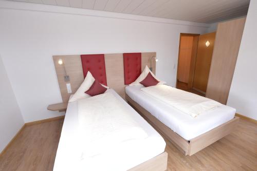 two beds in a room with white sheets and red accents at Gasthaus Hotel Sonne in Villingen-Schwenningen