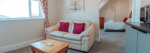 a living room with a couch with two pink pillows at Plas Gorwelion guest house - Adult only in Llandudno