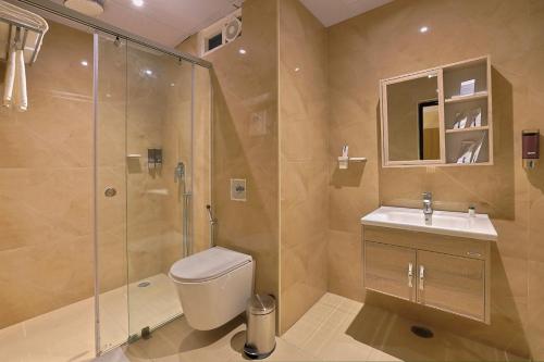 a bathroom with a shower and a toilet and a sink at Hotel Grand Continent Premiere, Banjara Hills, Hyderabad in Hyderabad