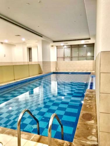 a large swimming pool with blue tiles in a building at Entire 1-Bedroom Apartment with Balcony, Sharjah in Sharjah
