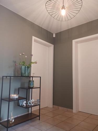 a room with a ceiling fan and a shelf with flowers at La Louche à Véro in Ligneuville