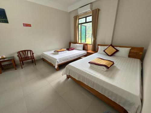 a bedroom with two beds and a chair and a window at Ba Be Lake - Nhà Nghỉ Thư Nhạc in Bak Kan